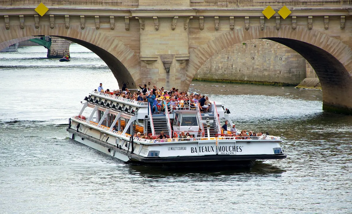 A sightseeing boat passing under a bridge on the Seine